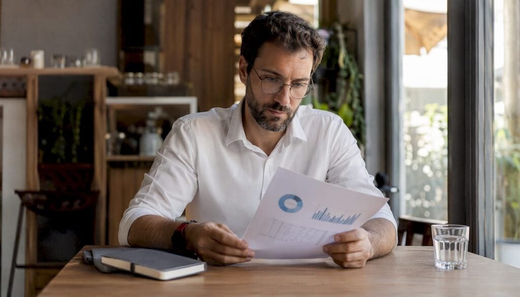 Έλληνας αναλυτής μελετά προσεκτικά τις εκτυπωμένες αναφορές των δεδομένων.
